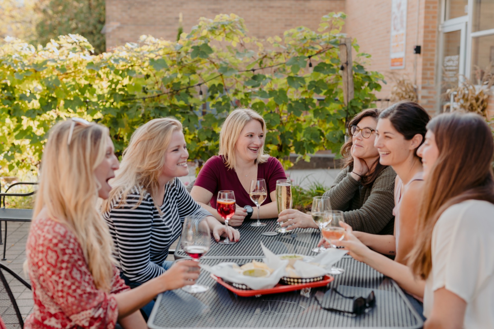 Group of women sharing wine and appetizers on a brick winery patio in Traverse City