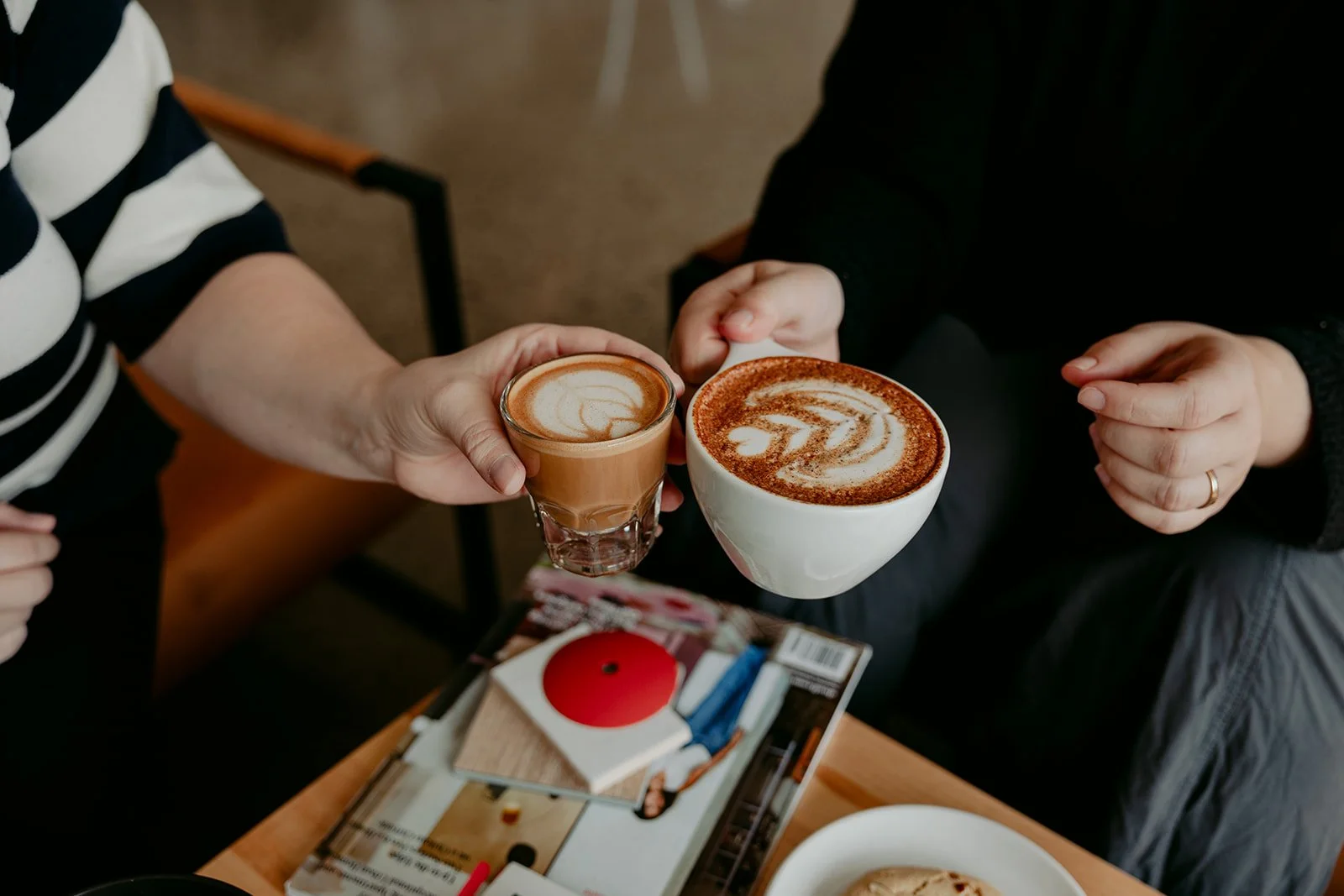 Two lattes with beautiful latte art being clinked together