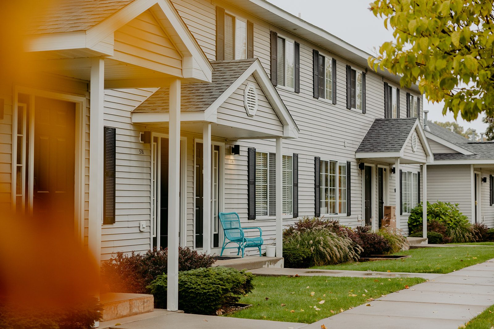 Row of white modern townhouses with covered front porches and turquoise chairs on a fall afternoon in Traverse City