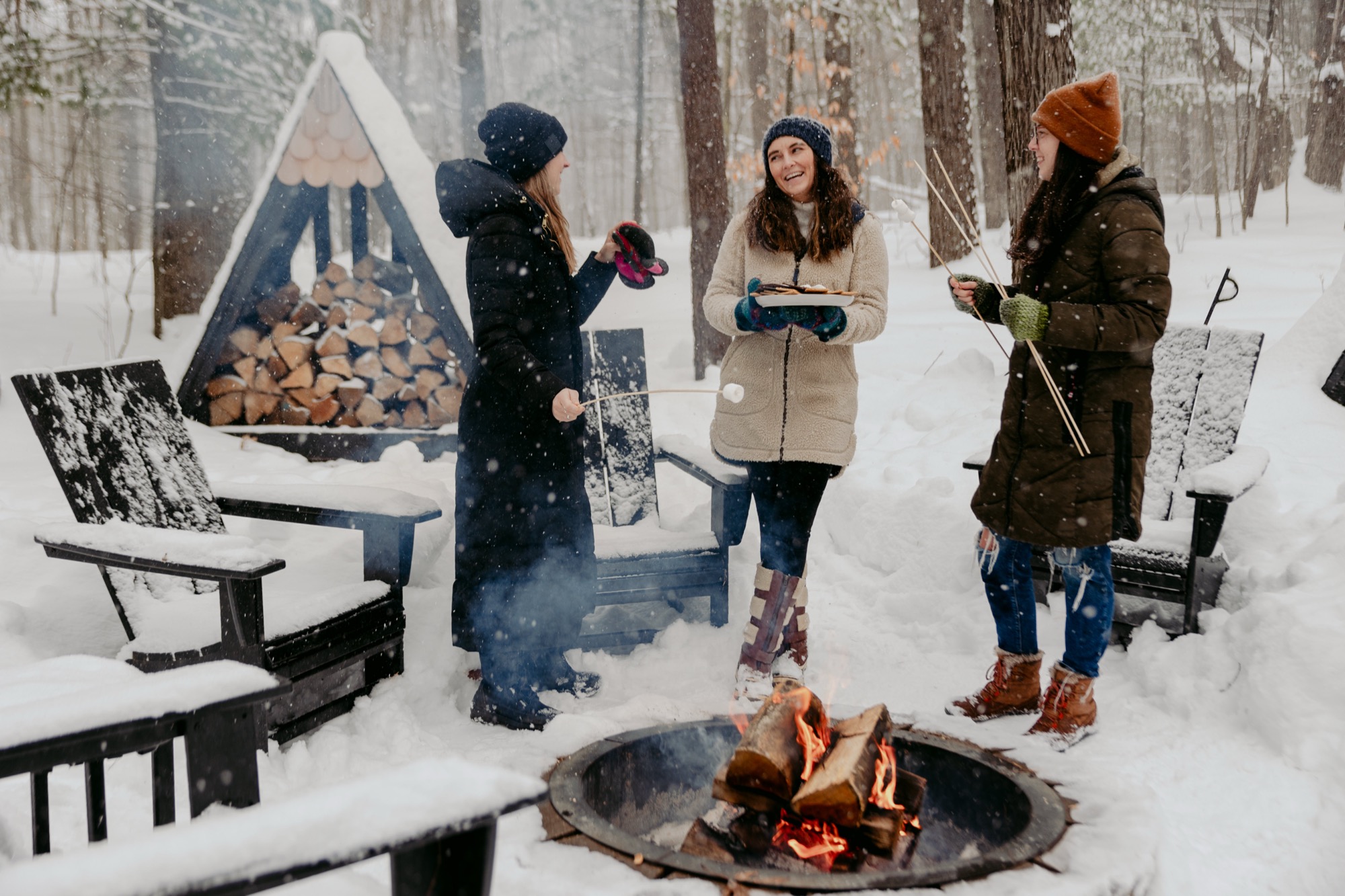 Friends gathered around a crackling fire pit in the snow at the A-Frame