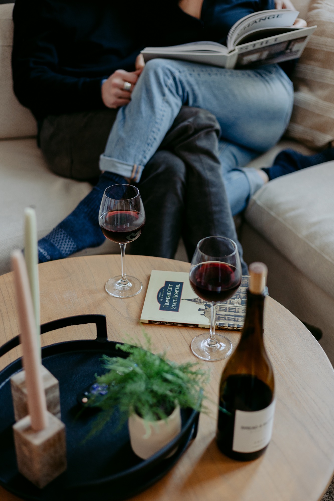 Couple relaxing on the sofa with wine, candles, and a good read
