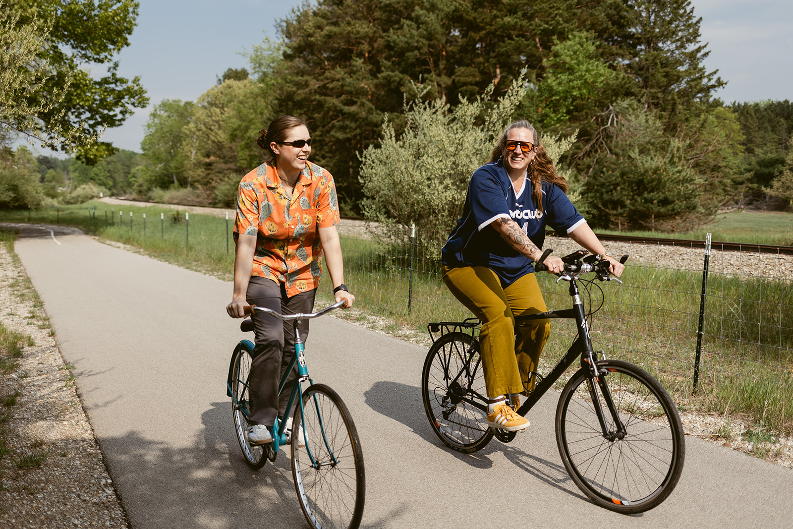 Two cyclists riding the paved TART Trail through green woods near Traverse City